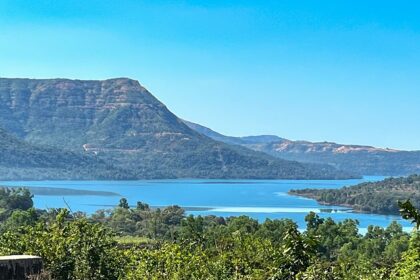 A breathtaking view of a lush green valley in Pune with a water body flowing through.