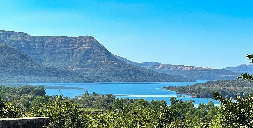 A breathtaking view of a lush green valley in Pune with a water body flowing through.