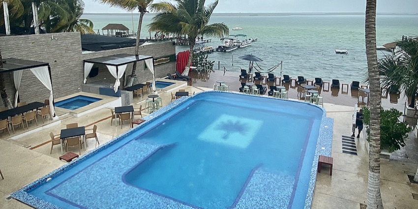 Swimming pool at the Beach Club surrounded by sun loungers and palm trees on the beach