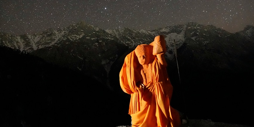 A person stands triumphantly on a mountain, evoking the spirit of Hanuman temples in Pune.