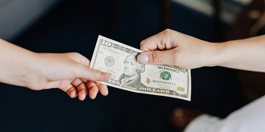 A person handing another person a 10-dollar bill with only hands and note visible