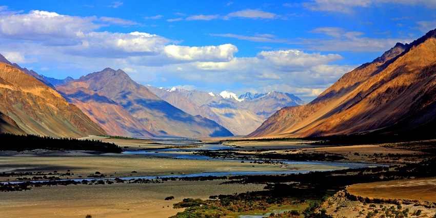 A picture of a valley in Ladakh with a water body and views of mountians