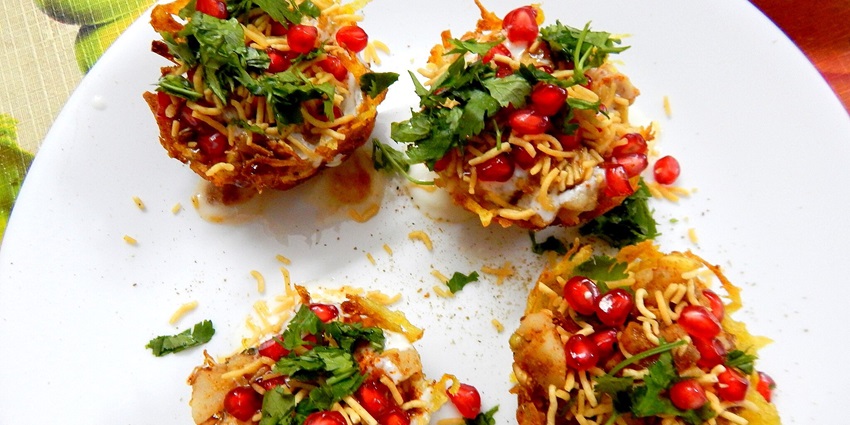 Four delicious aloo tokri chaats are placed on a white platter and garnished properly.