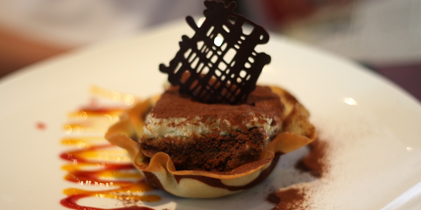Tiramisu, served in a pastry shell, garnished with caramel and chocolate topper