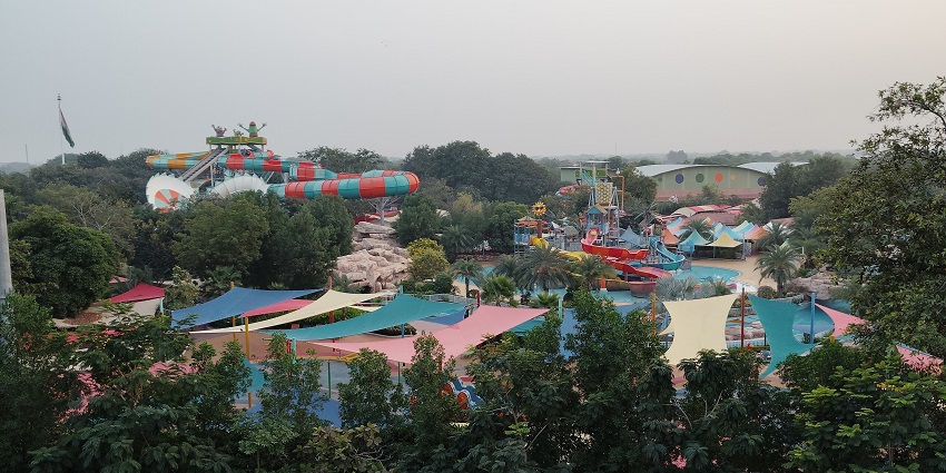 A picture of a water park with a pool, a lazy river and numerous tall slides