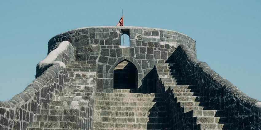 Majestic view of Rajgad Fort perched on a hilltop surrounded by lush green valleys.