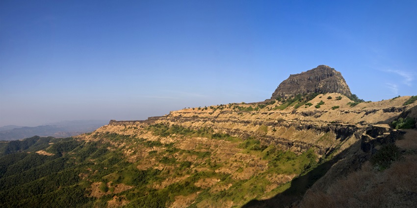 Rocky hilltop citadel rising sharply above surrounding terrain under clear sky