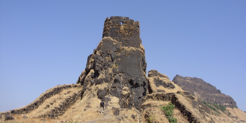 An image of Rajgad Fort with ancient structures and green hills, captured in the blue sky.