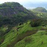 Side view of Rajmachi Fort, a popular tourist attraction near Maharashtra, amidst greenery.