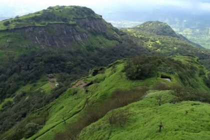 Side view of Rajmachi Fort, a popular tourist attraction near Maharashtra, amidst greenery.