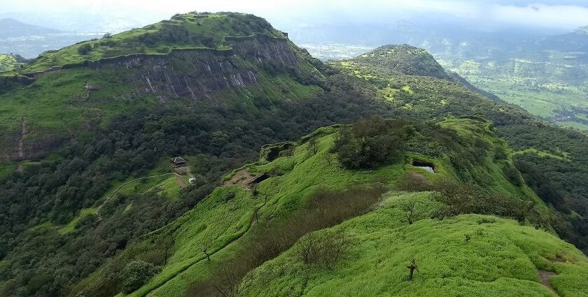 Side view of Rajmachi Fort, a popular tourist attraction near Maharashtra, amidst greenery.