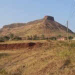 View of Ramshej Fort with rocky terrain and scattered greenery in Nashik, Maharashtra.