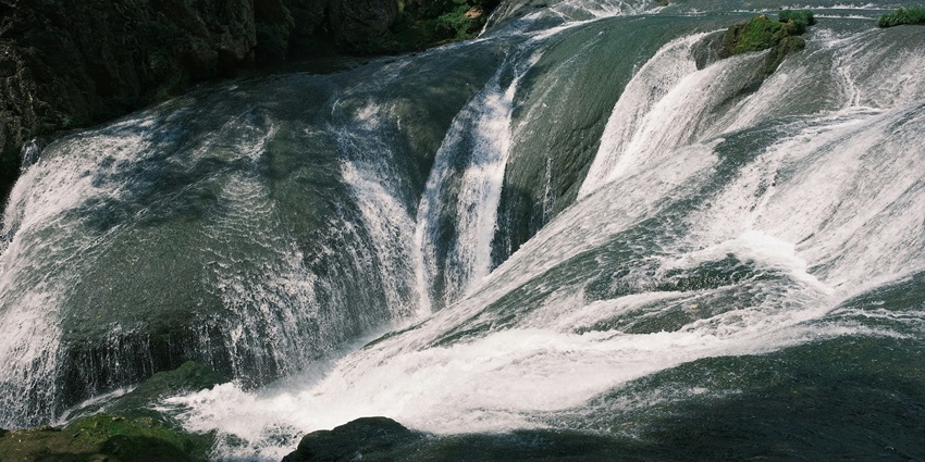 A serene view of the Randha Falls, featuring shimmering waters and lush greenery.