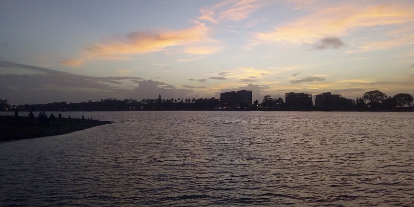 Evening view of Rankala Lake with red sky and buildings near Mohini Water Park.