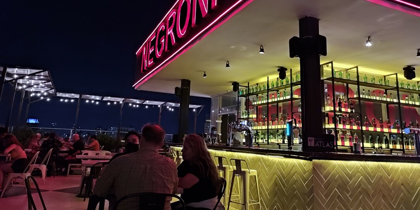 A picture of people dining at a rooftop restaurant with a bar visible in the background