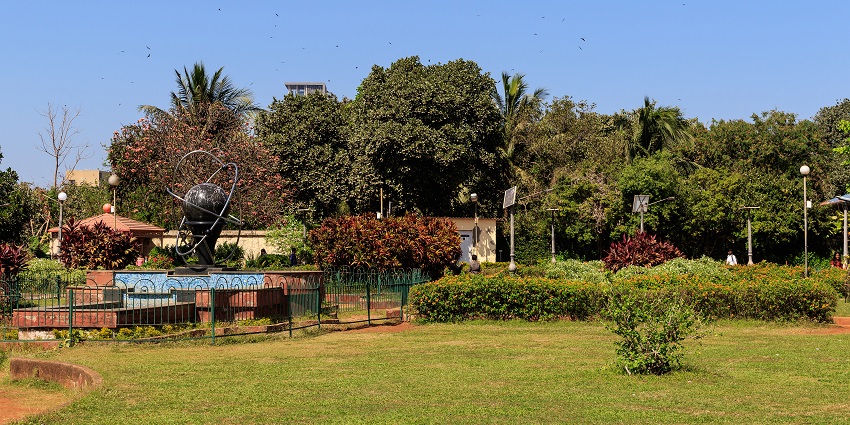 View of Mumbai's Hanging Gardens with lush greenery, overlooking the city skyline in the distance.