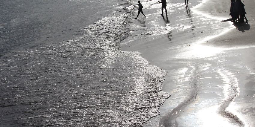 View of Malvan Beach, featuring sandy shores, clear turquoise waters, and gentle waves.