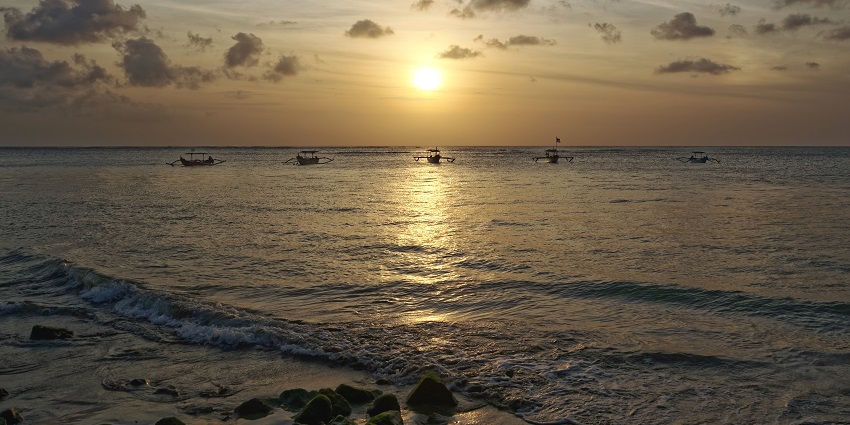 A fisherman throws the net to catch fish on the beach in Kuta, Bali, Indonesia.