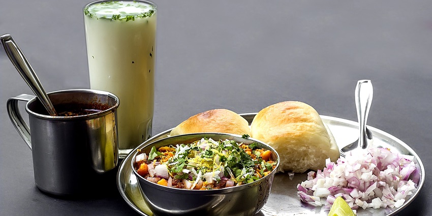 A colorful plate of Phadtare Misal, featuring spicy misal with pav and fresh toppings.
