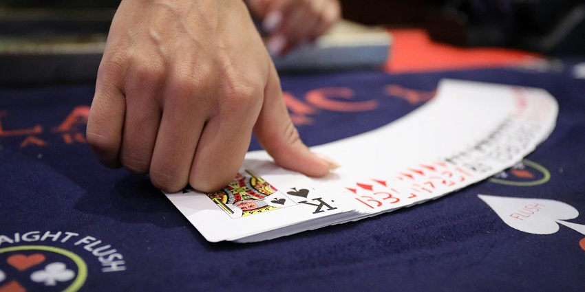 A glimpse of a person shuffling and displaying the cards on a table for a game of poker.