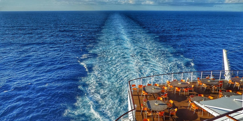 Image of a ship cruise surrounded by clear blue water under blue and decorated cafe area on the ship