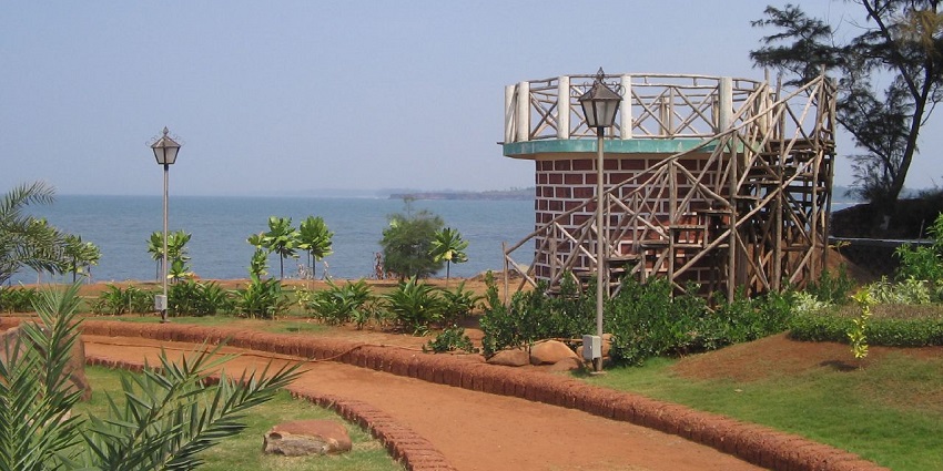 A serene rock garden in Malvan with sculptures, flowers, and sunset views.