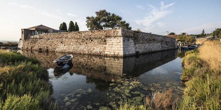 A glimpse of the historic Rohtak Fort in Haryana surrounded by glistening blue waters.