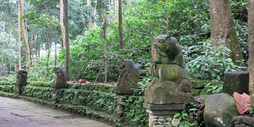 A concrete path with stone statues of monkeys in the Sacred Monkey Forest in Ubud.