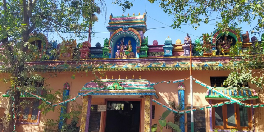 A frontal view of a traditional Hindu temple, with trees in front of its exterior walls