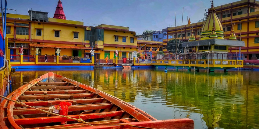 A temple complex with a huge pond and water boats inside surrounded by other buildings