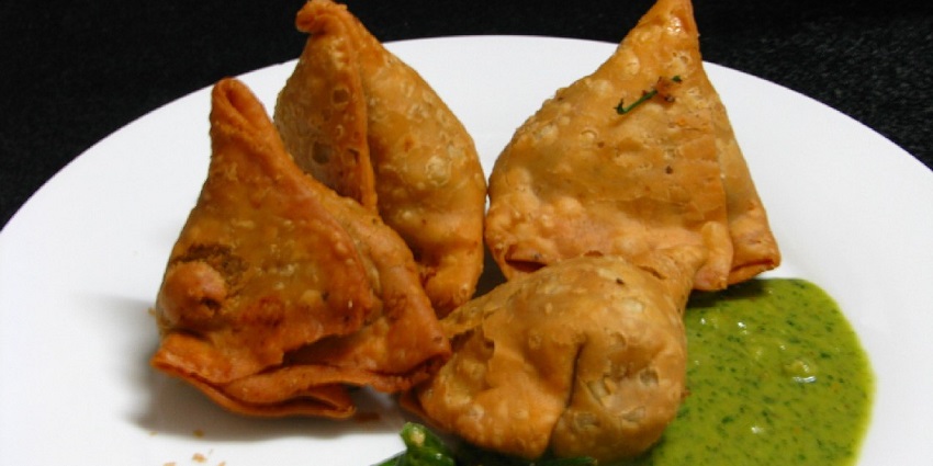 Samosa served with green mint chutney, is usually eaten with hot tea as a snack