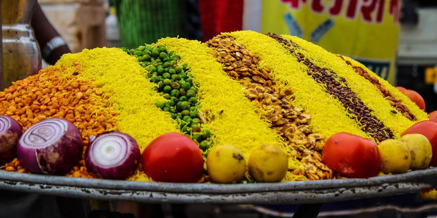 A picture of a cart with vegetables and snacks stacked up for preparing a delectable street snack