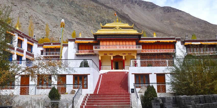 A picture of a monastery taken from the front with views of a mountain in the background
