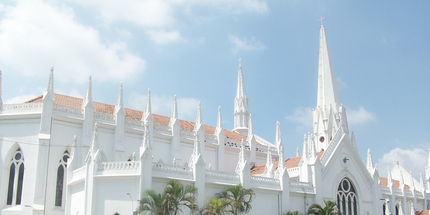 The white facade of Santhome Basilica with its towering spires and Gothic architecture.