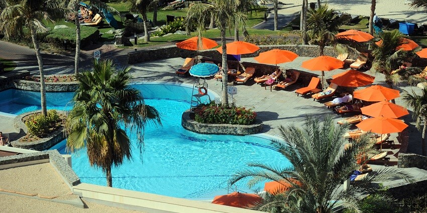 An aerial view of the Sandal Suites By Lemon Tree featuring azure waters and tall trees.