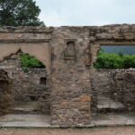 Ruins of Bhangarh Fort with remnants of stone structures and green barren hills.