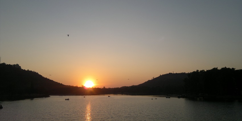 An image of Saputara Lake surrounded by hills, popular for boating and trekking