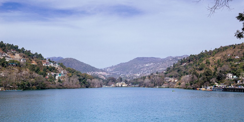One of the many clear lakes in India, with mountains and clouds in the background.