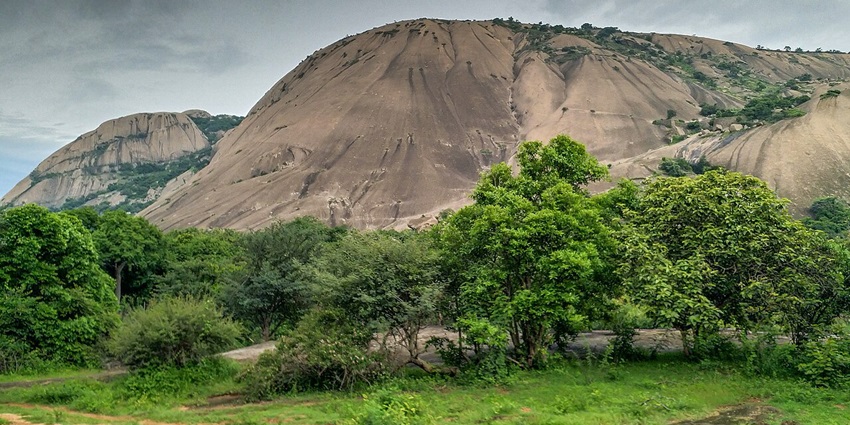 An image of the giant monolithic Savandurga hill rising above forests, ideal for trekking adventures.