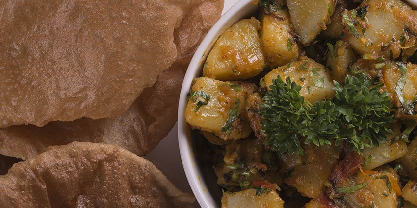 Puri and Bhaji are placed on a platter while bhaji is topped with coriander leaves.