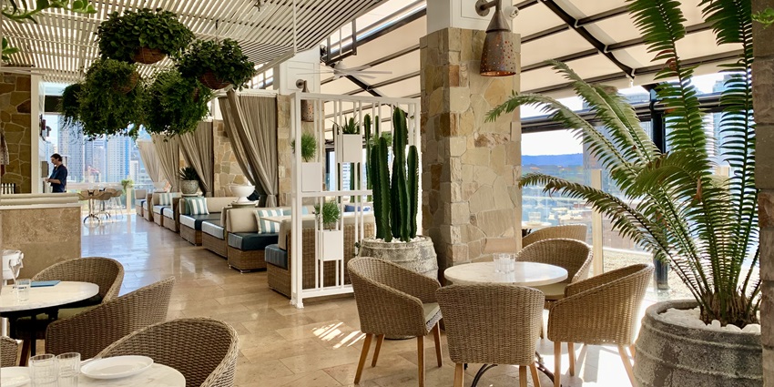 A picture of a rooftop restaurant in Mumbai with a cosy ambience, decorated with plants