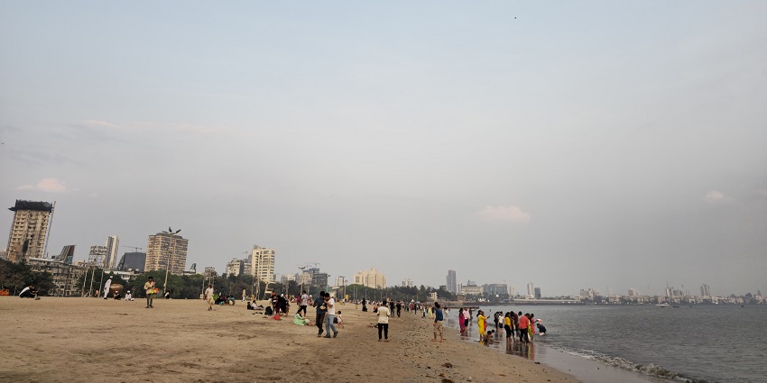 View of Chowpatty Beach in Mumbai, featuring the sandy shore and distant city skyline.