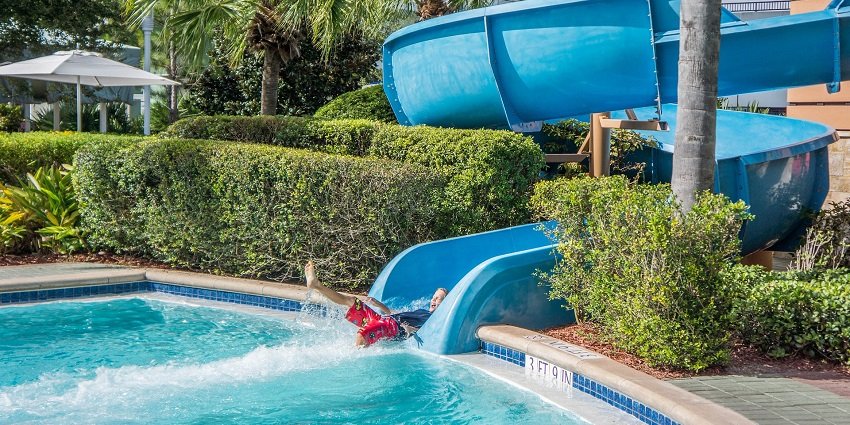 An image of a child in a pool going down a spiral water slide offering extreme thrill.