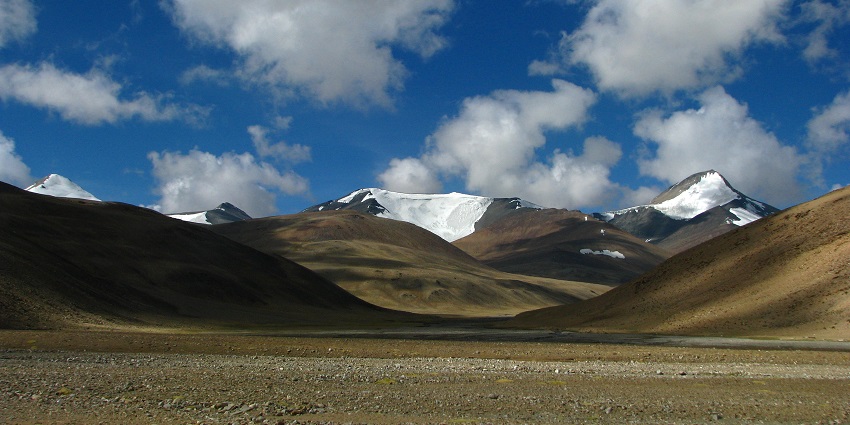 A serene view of brown grounds, thrilling rustic terrains, and majestic mountains.