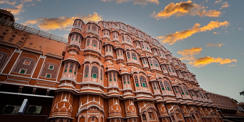 Hawa Mahal Palace in Jaipur, India, showcasing its stunning pink facade and intricate latticework against the evening sky.