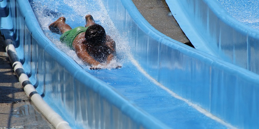 A young boy sliding on a slip-and-slide outdoors, enjoying a playful moment.