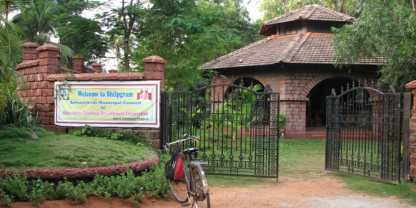 Entry gate to traditional huts at Shilpgram featuring local crafts and cultural heritage
