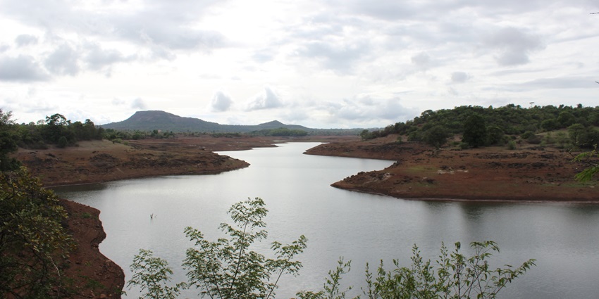 Kayaking in Lonavala at the YMCA Nilshi retreat surrounded by dry landscape and hills at a distance.