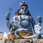 Shiva idol at Koneswaram Temple, overlooking the ocean, surrounded by rich greenery.