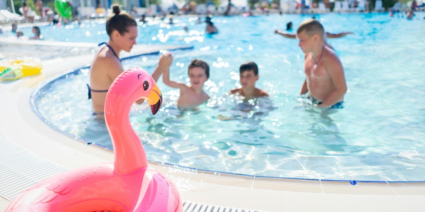 A view of a family enjoying a pool, surrounded by clear water and sunny skies